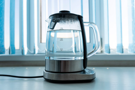 Pure water boils in an electric kettle on the table in the kitchenの写真素材