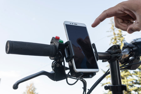 cyclist hands use gps navigator on smartphone while biking. man presses his finger on the smartphone...