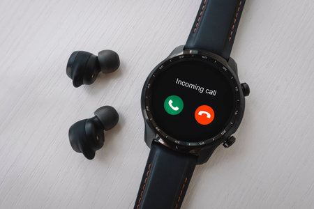 incoming call on a modern smart watch. black smart watch and wireless headphones on a white background.の写真素材
