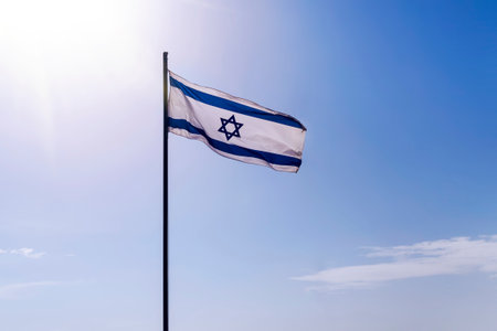 Israel flag flapping in the wind at good sunny day and old city background.
