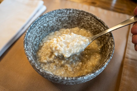 Whole oatmeal, large bowl of porridge with butter for breakfast, morning meal. Top view, close up, gray table. Vegan healthy tasty diet.の写真素材