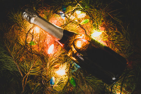 a bottle of champagne under the Christmas tree in the light of garlands. copy space for bottle designの写真素材