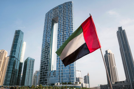 Unique view of UAE, United Arab Emirates national flag waving in the air with Dubai skyline in background. UAE National Dayの写真素材