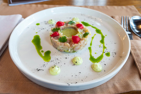 The salad of various ingredients is beautifully arranged in the form of a ring on a white plate.