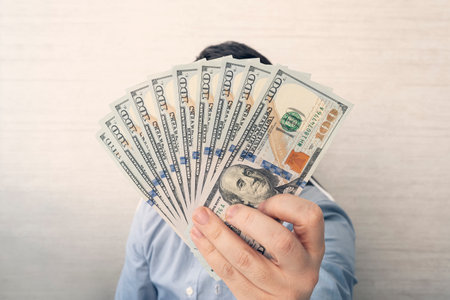 a young man holds 1,000 dollars in his hands on a white background in the office.
