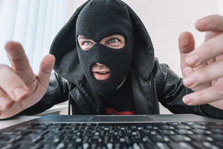 Thieves hold credit cards using a laptop computer for password hacking activities. Cyber crime...
