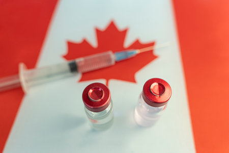 Pharmacology and Medicine Canada concept. vaccine against coronavirus covid. Vaccine ampoules, syringe against the background of the national flag. national pharmaceutical industry.の写真素材