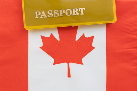 Flag of canada with passport. Travel visa and citizenship concept. residence permit in the country. a yellow document with the inscription passport is on the flag. close up, top viewの写真素材