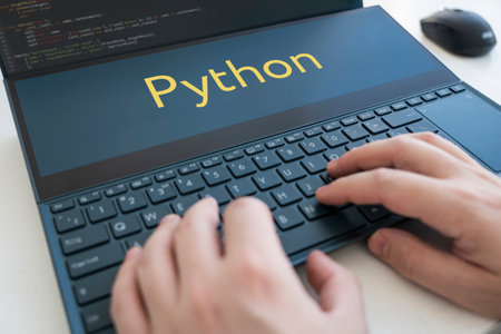 a programmer writes a program in python. Male hands on a black keyboard