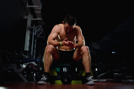 Handsome young man looking forward after exercise class at dark gym. Bodybuilding, weightlifting, sportsの写真素材