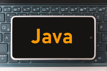 Java Programming language for mobile development, concept. Smartphone on the laptop keyboard, the programmer workplace. inscription java on the mobile phone screen ,の写真素材