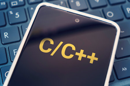 C Programming language for mobile development, concept. Smartphone on the laptop keyboard, the programmer workplace. inscription on the mobile phone screen,の写真素材
