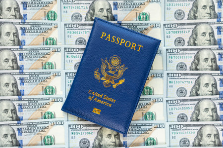 US passports in a pile of US dollar banknotes. US document. an American passport against the background of a large pile of American dollars. The concept of lending or buying fake documentsの写真素材