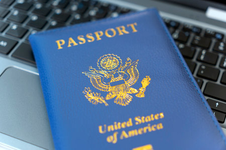 Passport of USA on Notebook's keyboard, close up. Identification of the user on the Internet. Prohibition of access to the Internet without passport data. issuing a passport via Internetの写真素材