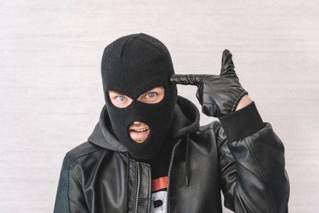 A thief in a black jacket. A man in a black balaclava with an evil expression on his face. An...