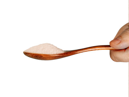 Hand and sugar on wooden spoon isolated on a white background.の写真素材