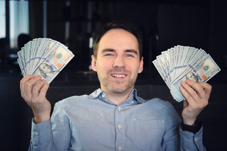 Hands holding dollar cash. 1000 dollars in 100 bills in a man's hand close-up on a dark background.