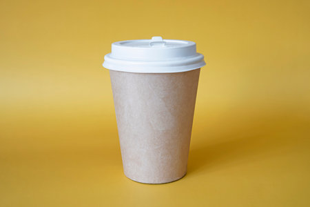 brown paper coffee mug on a yellow background. Empty space for text and design on a cup of coffee. form for the name of the coffee or company or coffee shopの写真素材