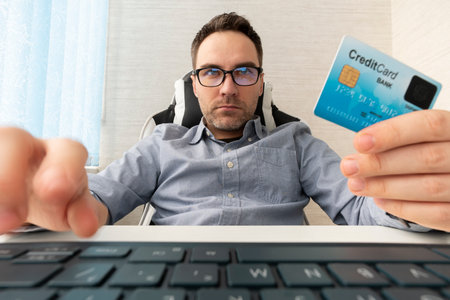 Young businessman holding a credit card and typing. On-line shopping on the internet using a laptop. man enters the card details on the websiteの写真素材