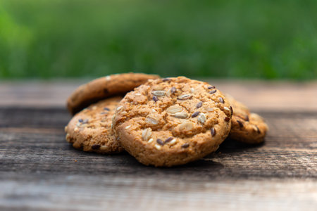 Heart shaped cookies on wooden table, sweet homemade Heart-shaped cookies with oat flakes. Oatmeal cookies with sesame seeds. oatmeal cookies with seeds on wooden table on a green background of natureの写真素材