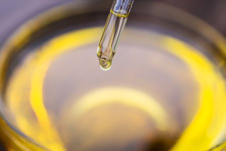 Yellow texture of a drop of whey or olive oil on a yellow background. Transparent sample of cosmetic gel with bubbles. Golden acid cream. Vitamin c. A drop of honey. Hyaluronic acid.の写真素材