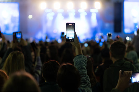 hands using camera phone to take pictures and videos at live concert, smartphone records live music...