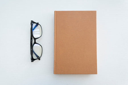 Reading glasses with books on the white table. Empty space on the cover for design and text