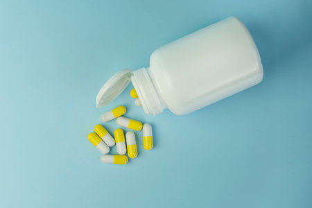 Yellow turmeric therapeutic capsules, herbal vitamin pills or drugs for treatment on blue background, medicine and healthcare concept, close up , top view.の写真素材