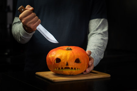 sad pumpkin on a wooden board in the dark in the kitchen. Preparing for the celebration of Halloween. creating jack's lanternの素材