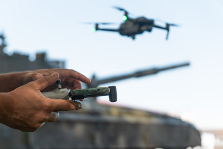 a man with a UAV control panel in his hands, a drone flying above the tank in the background in...