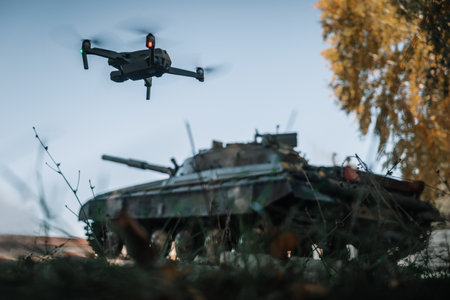 a drone flying above the tank in the background in nature. help of reconnaissance drones in modern warfare.の写真素材
