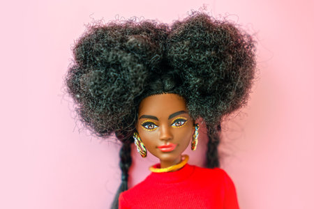 October 9, 2023. Barnaul, Russia: african american Barbie doll with black hair in a red suit standing on a pink background.のeditorial素材