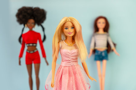 October 9, 2023. Barnaul, Russia: three dolls blonde, African-American and red-haired dolls on a blue background. Barbie and her friends.のeditorial素材