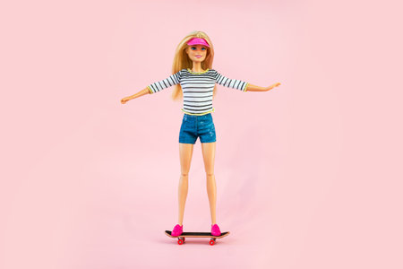 October 9, 2023. Barnaul, Russia: Barbie doll in sportswear riding a skateboard on a pink backgroundのeditorial素材