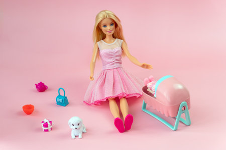 October 9, 2023. Barnaul, Russia: Barbie doll with loose blond hair in a pink dress standing on a blue background. barbie mother with a baby in bed.のeditorial素材