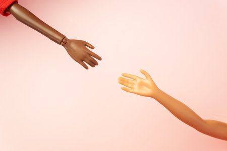 Two doll hands reach for each other on pink background. Different skin tones and races. Stop racism, diversity and unity, equality and feminism creative concept. Place for text, top view, layoutの写真素材
