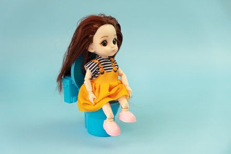 A child toy doll with dark hair on a blue background. Plastic children's toy. Doll games for imagination. copy spaceの写真素材