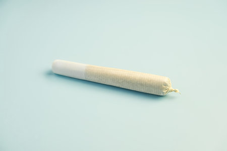 Preparing cannabis joint with tobacco and rolling paper with marijuana bud on blue background. The insinuation of marijuana abuse. cannabis legalization conceptの写真素材
