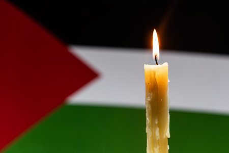 Mourning in country palestine, gaza strip. A burning candle on the background of the Palestinian flag. Victims of cataclysm or war concept. National mourning. war in Middle Eastの写真素材
