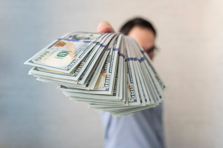 businessman with american dollars. a man holds American dollars in his hand. The boss pays the salary. The concept of bribery and corruption, giving money.の写真素材