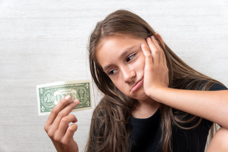 Sad child with money dollar. Not enough money. white backgroundの写真素材