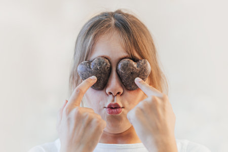 A girl is holding gingerbread in the shape of a heart. child closes his eyes with cookiesの写真素材