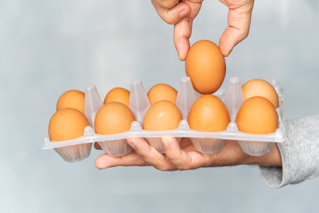 man checks the eggs in the box. a customer in a supermarket touches chicken eggs in a cardboard box....