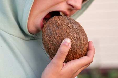 Eating hard coconut. strong white teeth bite a coconut. An open mouth with a nut. crack the hazelnut shell.の写真素材