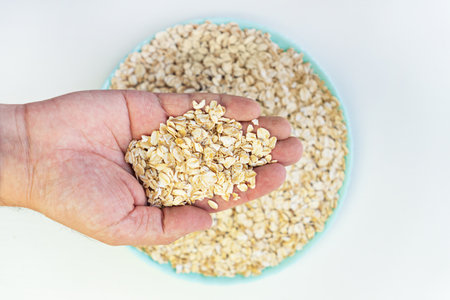 dry oatmeal flakes in bowl And in the hand on white background. Top view.の写真素材