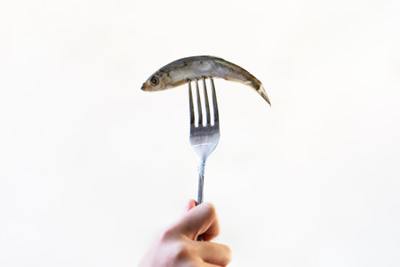 sprat fish on fork isolated on white background.の写真素材