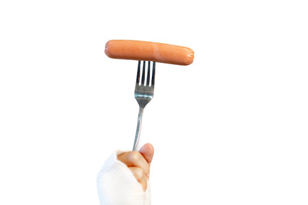 Female hand hold fork with sausage isolated on white backgroundの写真素材