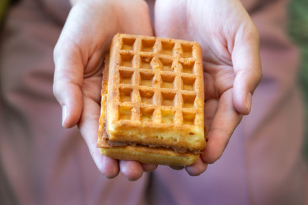 Crop person holding appetizing sweet Belgian waffles with chocolateの写真素材