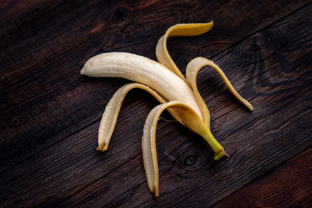 Fresh peeled overripe banana with spots, on a wooden tableの写真素材
