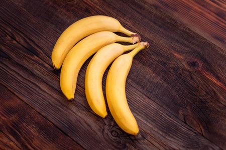Bananas on a wooden table. a ripe yellow bunch of bananas on the kitchen table.の写真素材